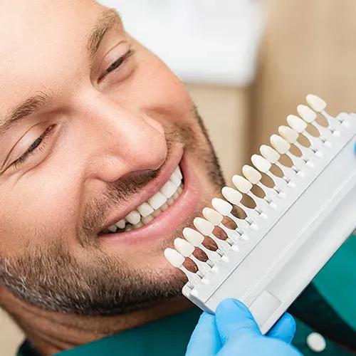 dentist holding shade-matching tool against patient's teeth