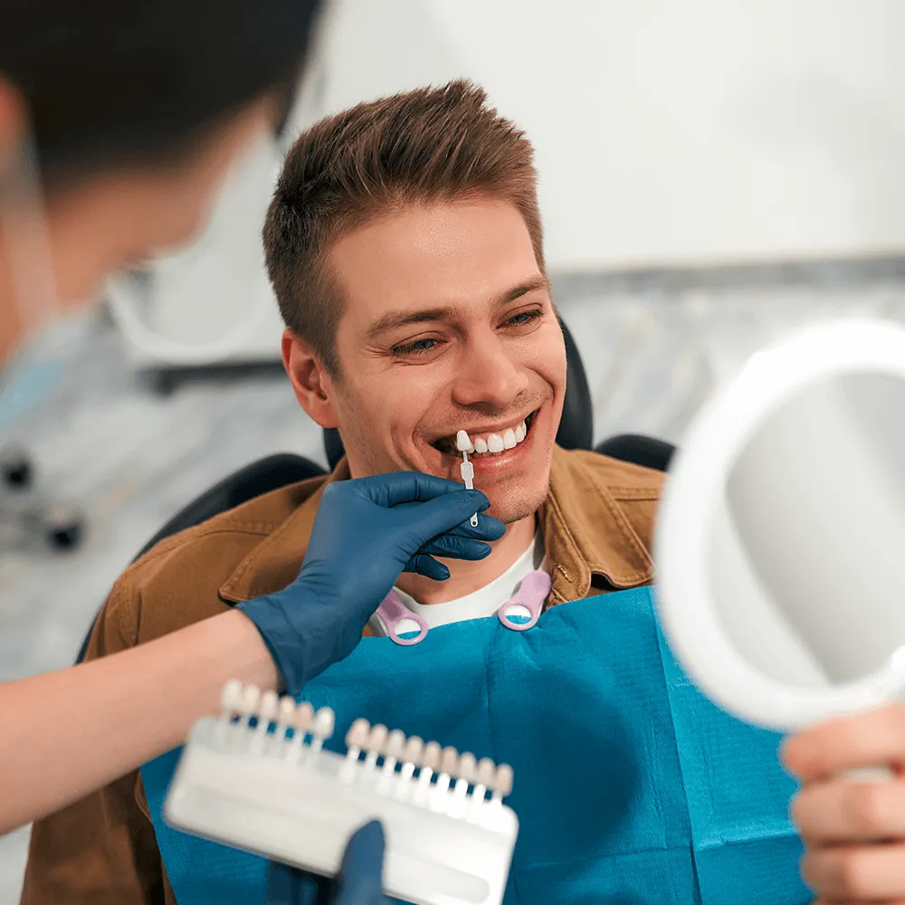 Dentist looking in mirror with veneers held by dentist