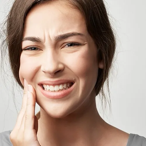 woman holding cheek in pain